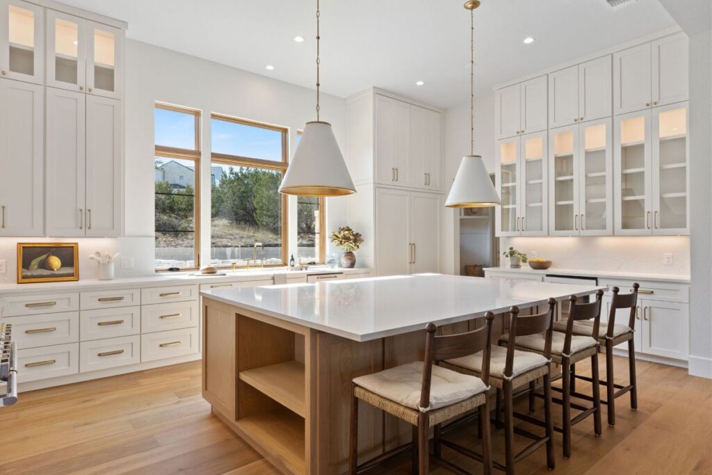 Build Native custom kitchen with white cabinetry and large windows. 